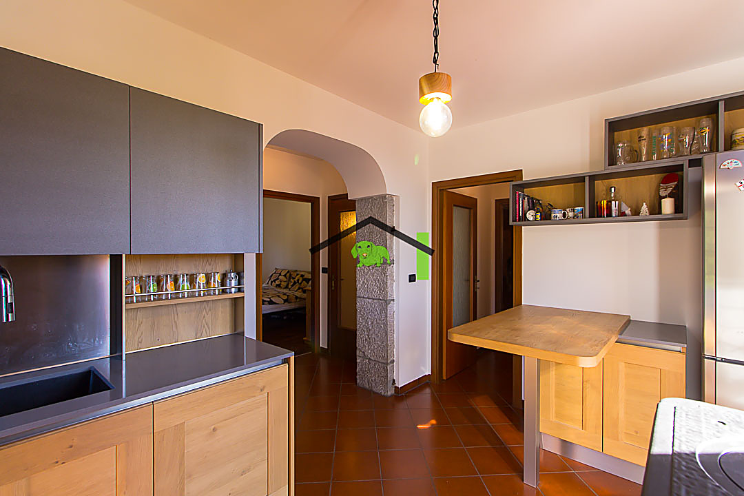 Cucina penisola in legno e arco in pietra